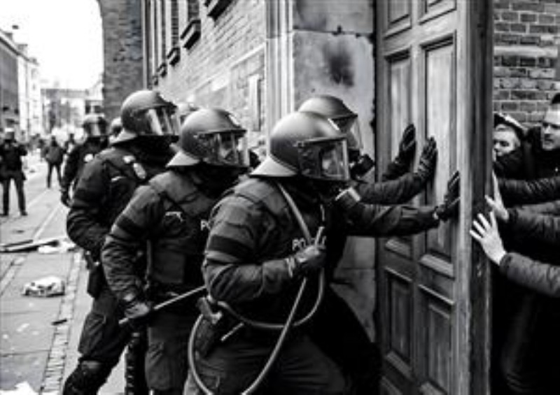 Konfrontation i Bybilledet - Oplev intensiteten ved politiets indgriben i byens gader. Dette dramatiske motiv fanger en vigtig samfundsdynamik og skaber en stemning af spænding og refleksion, perfekt til at vække samtaler i dit hjem.